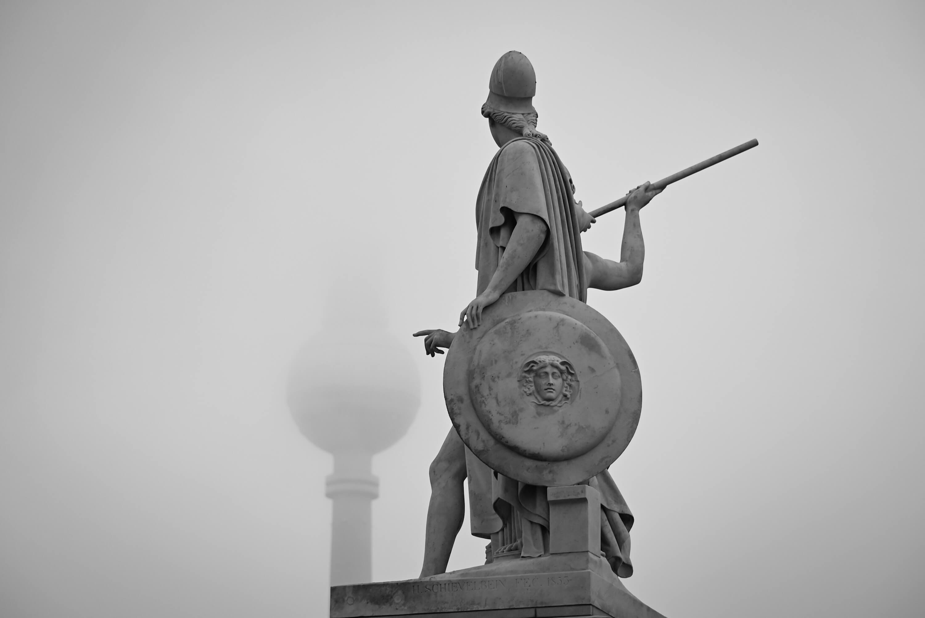 Starker Nebel in Berlin. Der Fernsehturm ist nur schemenhaft zu erkennen ist. Die Statue, Athene, die dem Jüngling im Gebrauch der Waffen unterrichtet, deutet mit dem Finger auf den Bauch des TV Towers