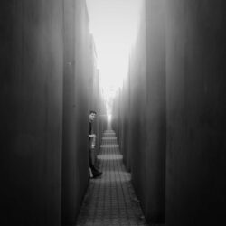 Gesicht, Hände und Füße eines Jungen, der direkt in die Kamera blickt beim Versteckspielen im Holocaust-Mahnmal in Berlin