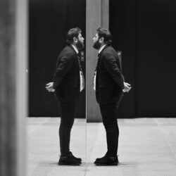 Ein Security Mitarbeiter im Anzug eines Museums schaut in den Spiegel