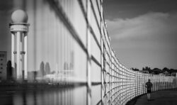 Perspektive auf dem Tempelhofer Feld richtet sich auf den Zaun in Fluchtpunkt zum Jogger, der vorbeiläuft